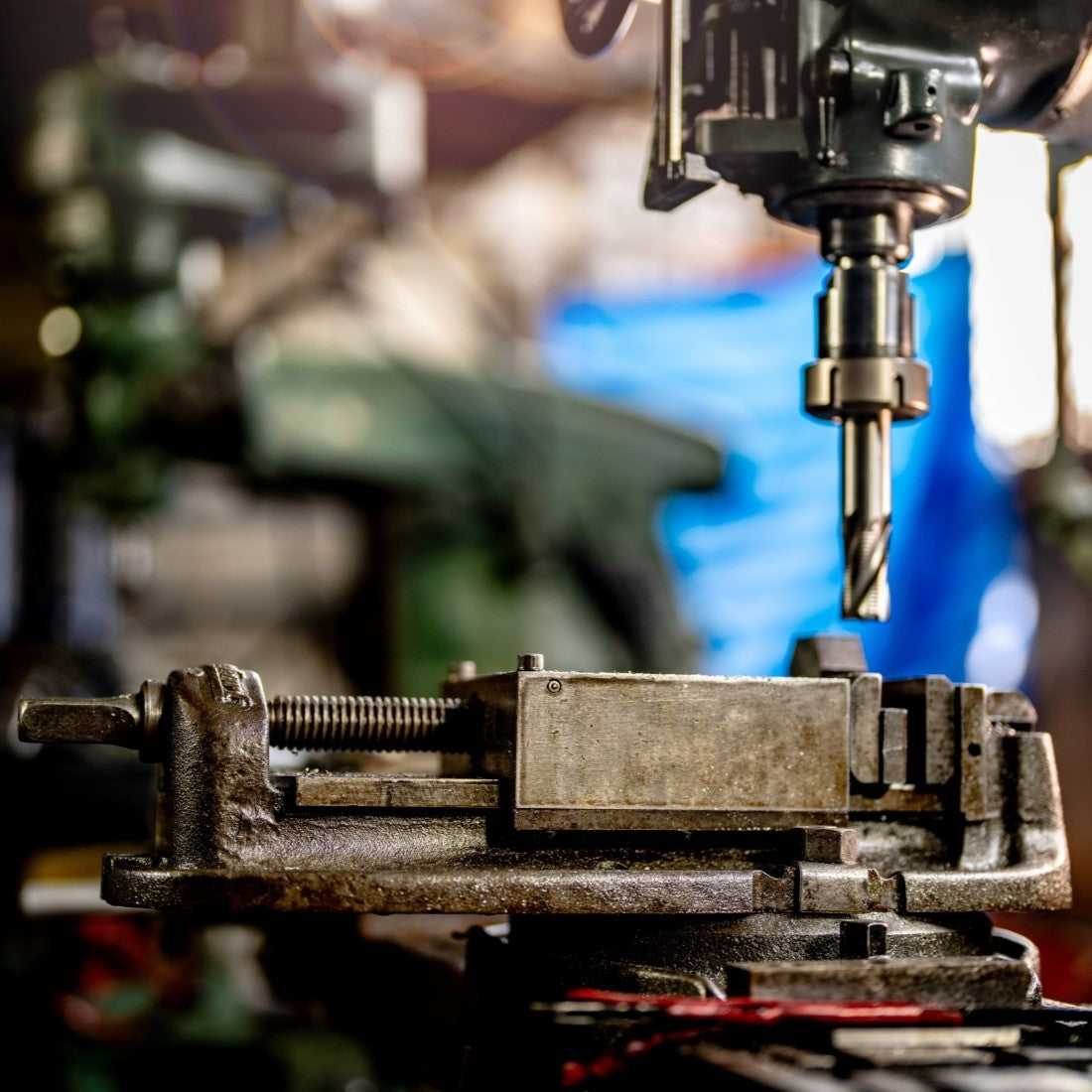Drilling machine in action with a blurred workshop background